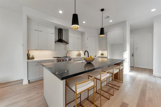 1128 W Pierce St, Houston, TX 77019 - kitchen featuring wall chimney exhaust hood, modern cabinets, light wood finished floors, backsplash, and baseboards