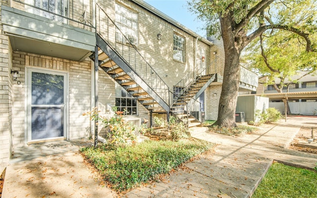view of exterior entry featuring brick siding and central AC