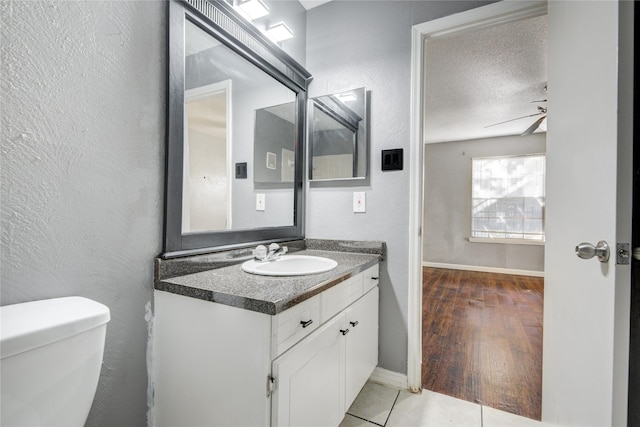 bathroom featuring a ceiling fan, toilet, a textured wall, and a textured ceiling