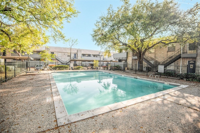 community pool with a residential view, fence, and a patio