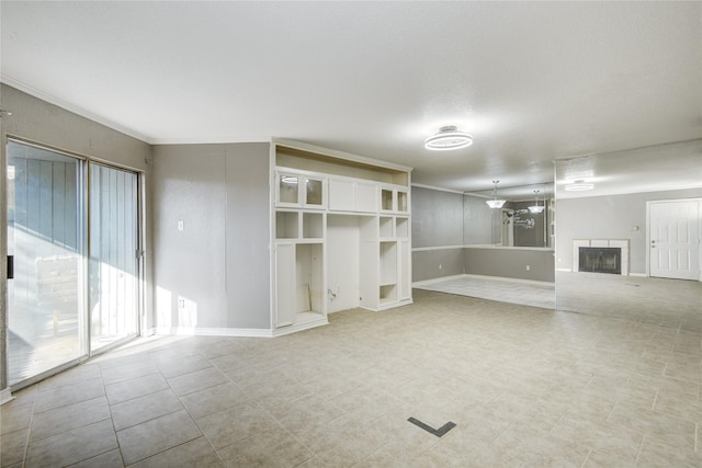 unfurnished living room with baseboards, a fireplace, and crown molding