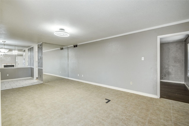 below grade area featuring tile patterned flooring, ornamental molding, baseboards, a textured ceiling, and visible vents