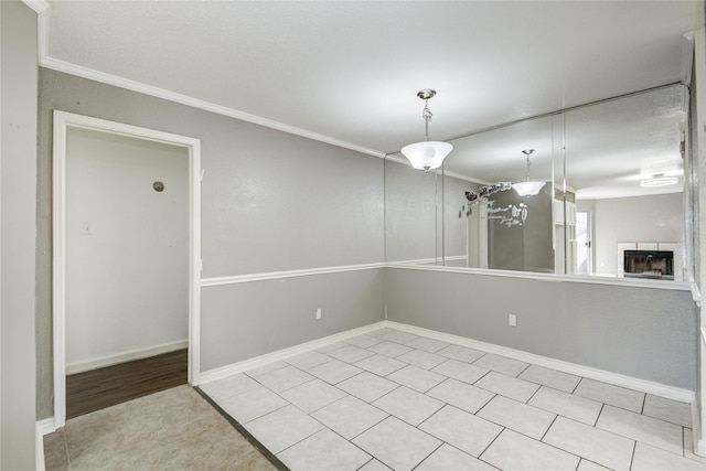 unfurnished room with baseboards, ornamental molding, and a tiled fireplace