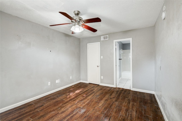 unfurnished bedroom featuring ensuite bathroom, visible vents, baseboards, ceiling fan, and wood finished floors