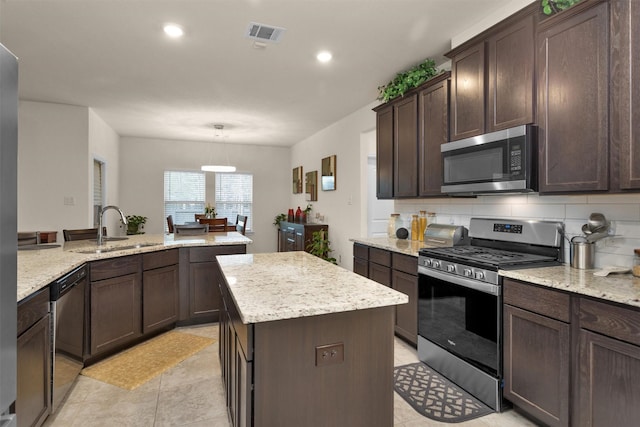 3311 Passage Ln, Conroe, TX 77301 - kitchen with appliances with stainless steel finishes, a sink, a kitchen island, dark brown cabinetry, and backsplash