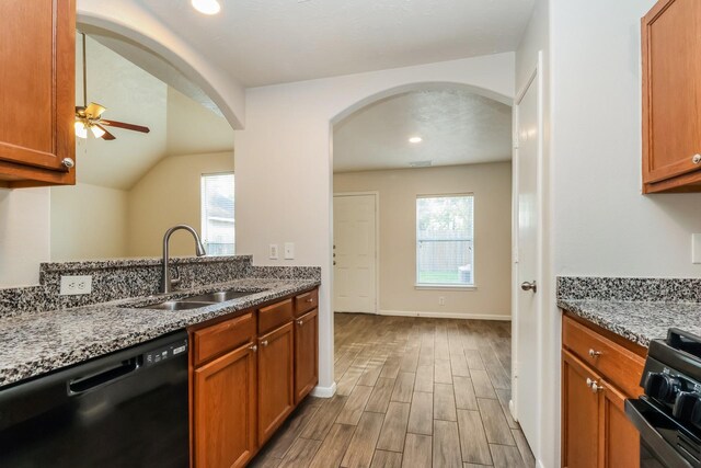 kitchen featuring light stone countertops, a sink, wood tiled floor, a wealth of natural light, and black appliances