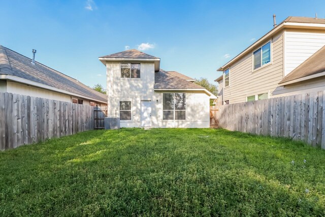 rear view of property featuring a fenced backyard, central AC unit, roof with shingles, and a lawn