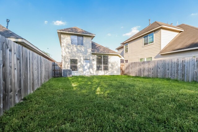 back of property with a lawn, a shingled roof, a fenced backyard, and cooling unit