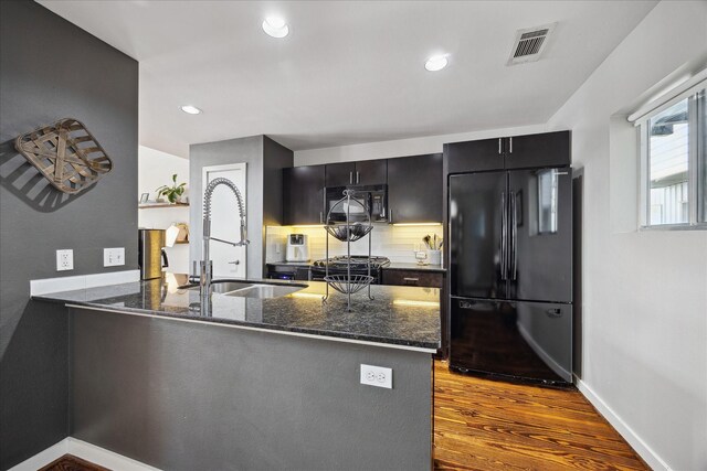 2976 Commerce St, Houston, TX 77003 - kitchen featuring black appliances, a sink, dark stone counters, a peninsula, and recessed lighting