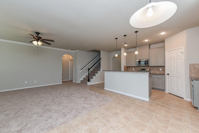 5911 Grantgrala Dr, Katy, TX 77493 - kitchen featuring decorative backsplash, gray cabinetry, stainless steel microwave, arched walkways, and ceiling fan