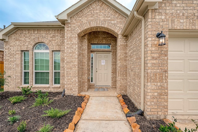 property entrance with an attached garage and brick siding