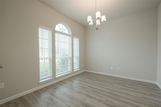 unfurnished room with baseboards, a chandelier, and wood finished floors