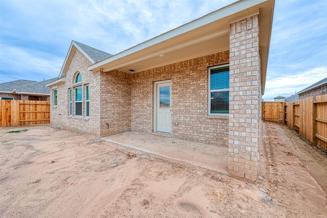 back of house with a fenced backyard, a patio area, and brick siding