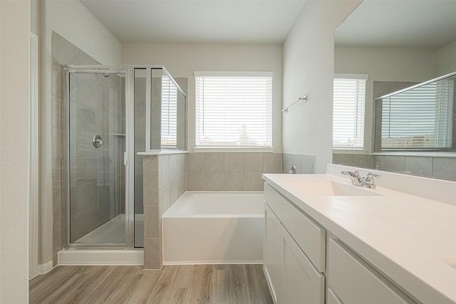 full bathroom featuring a bath, wood finished floors, a stall shower, and vanity