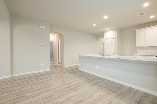 interior space featuring light wood-type flooring, recessed lighting, arched walkways, and visible vents