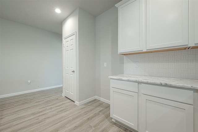 kitchen with backsplash, light wood-style flooring, white cabinetry, and baseboards