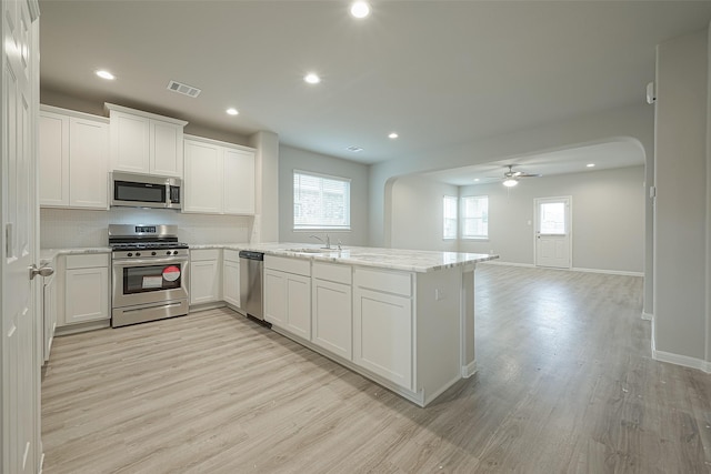kitchen with a sink, appliances with stainless steel finishes, a peninsula, visible vents, and arched walkways