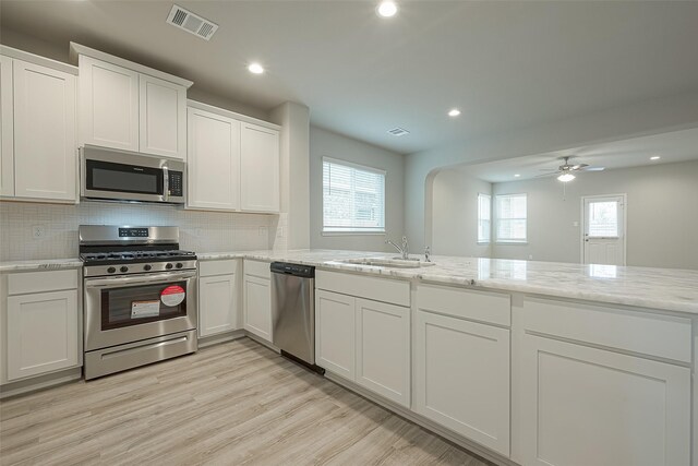 kitchen with white cabinetry, light wood-type flooring, stainless steel appliances, a sink, and visible vents
