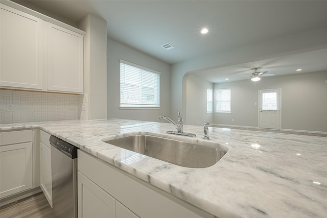 kitchen with visible vents, dishwasher, light stone countertops, white cabinetry, and a sink