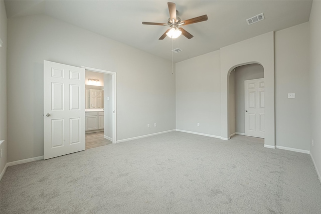 spare room with a ceiling fan, arched walkways, light colored carpet, and visible vents