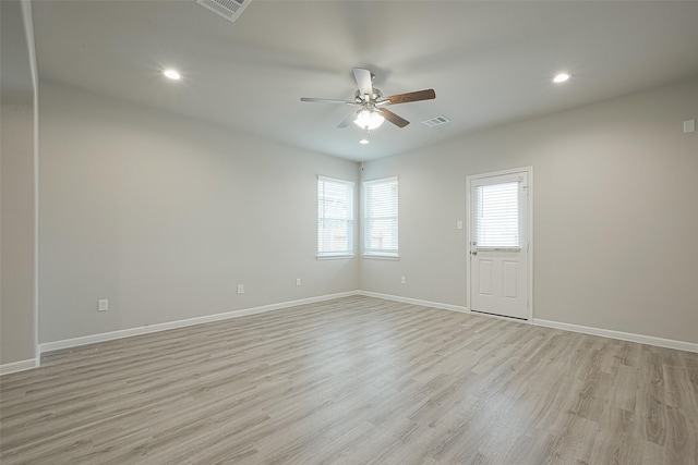 empty room with light wood-type flooring, a ceiling fan, baseboards, and visible vents
