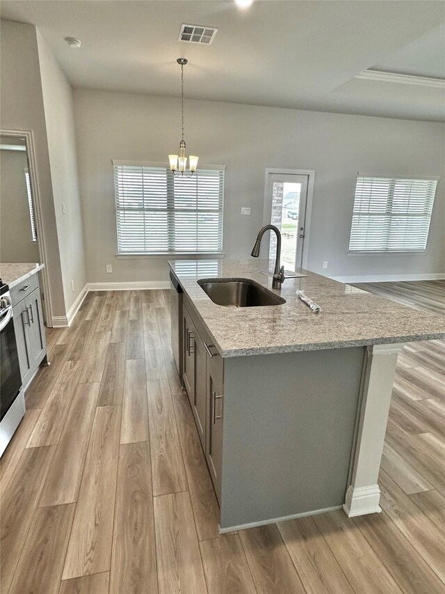 4210 Leslies Way, Dickinson, TX 77539 - kitchen with a sink, light wood-style floors, light stone countertops, a center island with sink, and decorative light fixtures
