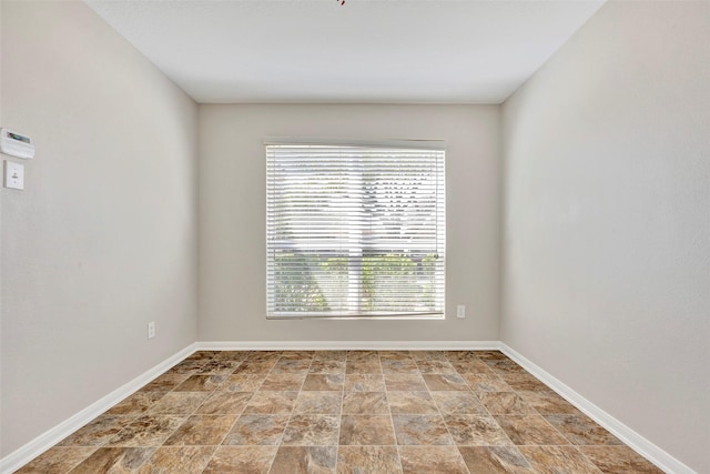 unfurnished room with stone finish flooring and baseboards