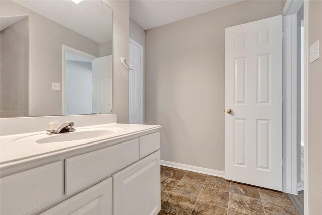 bathroom featuring stone finish floor, baseboards, and vanity