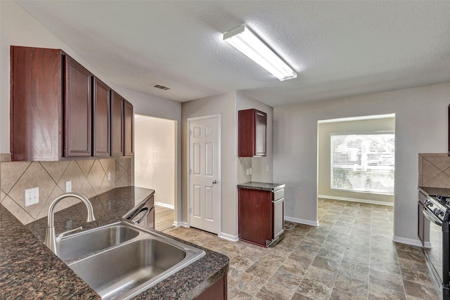 kitchen with backsplash, a sink, a textured ceiling, baseboards, and black range with gas cooktop