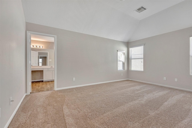 unfurnished bedroom with light carpet, baseboards, vaulted ceiling, and visible vents