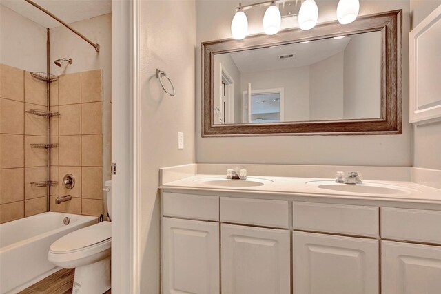 full bath featuring visible vents, a sink, toilet, and double vanity