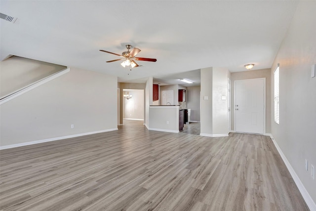 unfurnished living room featuring ceiling fan with notable chandelier, light wood-type flooring, visible vents, and baseboards