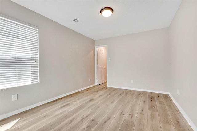 spare room with baseboards, light wood-type flooring, and a healthy amount of sunlight