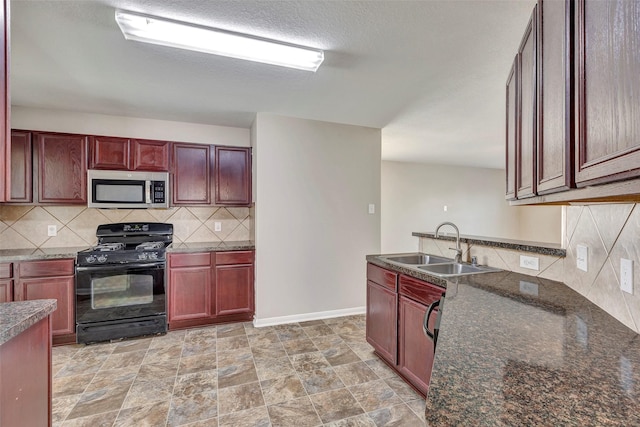kitchen with stainless steel microwave, a sink, reddish brown cabinets, and black range with gas stovetop