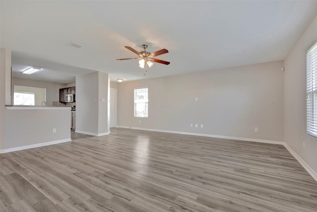 unfurnished living room with baseboards, light wood-style floors, and a ceiling fan
