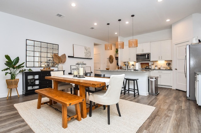 dining space with baseboards, visible vents, wood finished floors, and recessed lighting