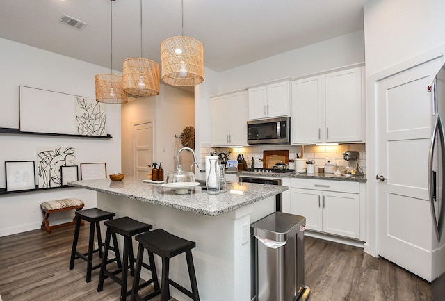 kitchen featuring decorative backsplash, visible vents, dark wood-type flooring, and appliances with stainless steel finishes