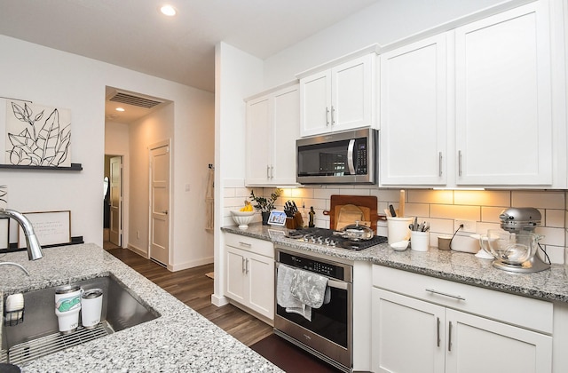 kitchen with white cabinetry, decorative backsplash, a sink, and stainless steel appliances