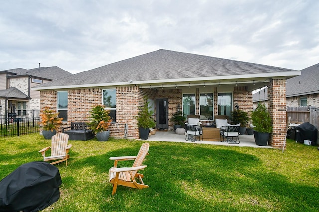 rear view of property featuring brick siding, fence, and a lawn