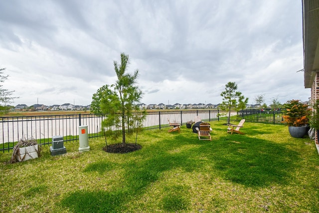 view of yard featuring a residential view, a water view, and fence