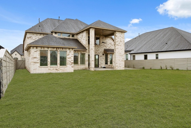 back of house with a lawn, brick siding, a fenced backyard, and a patio
