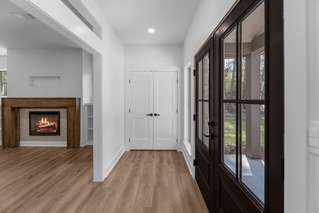 20302 Peach Dr, Huntsville, TX 77320 - foyer featuring light wood-style floors, baseboards, a warm lit fireplace, french doors, and recessed lighting