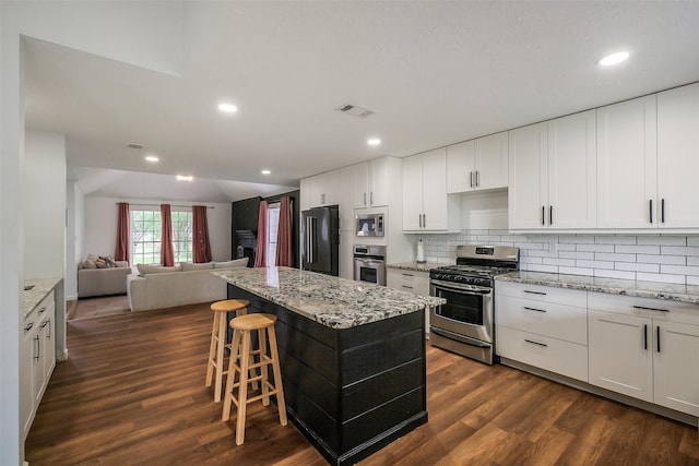 902 Rolling Mill Dr, Sugar Land, TX 77498 - kitchen with dark wood finished floors, stainless steel appliances, open floor plan, backsplash, and a kitchen island