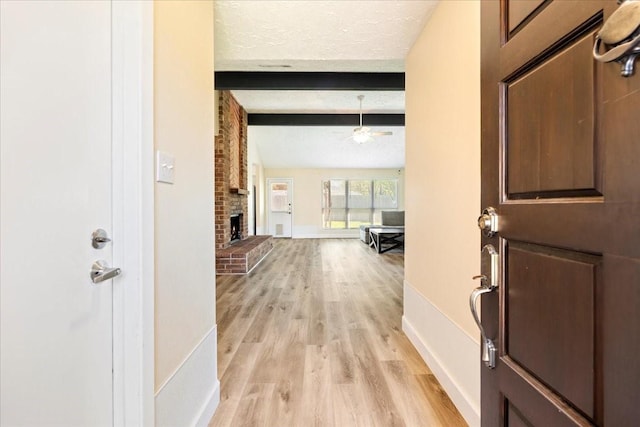 13623 Wimbledon Oaks Dr, Houston, TX 77065 - entryway with beamed ceiling, light wood-type flooring, a brick fireplace, a ceiling fan, and baseboards