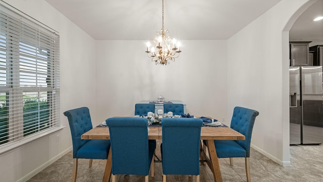 dining room with a chandelier, arched walkways, and baseboards