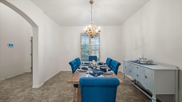 dining room featuring a chandelier, arched walkways, and baseboards
