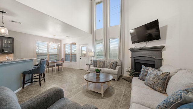 living room with a notable chandelier, baseboards, a fireplace, light tile patterned floors, and visible vents