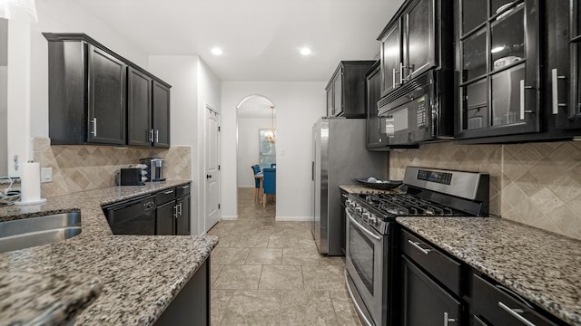 kitchen with arched walkways, light stone counters, glass insert cabinets, and black appliances