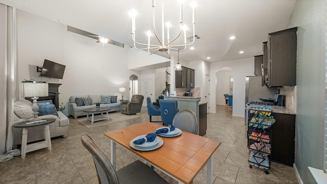 dining area featuring an inviting chandelier, arched walkways, a glass covered fireplace, recessed lighting, and baseboards