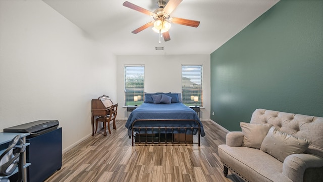bedroom featuring visible vents, baseboards, a ceiling fan, and wood finished floors